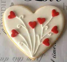 a decorated heart shaped cookie with red hearts on the top and white frosting in the middle