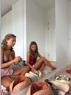 two young women sitting on the floor in front of their purses looking at something