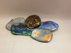 five different colored rocks sitting next to each other on a white surface with gold flecks