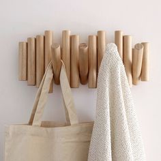 a tote bag hanging on the wall next to a coat rack with wooden pegs