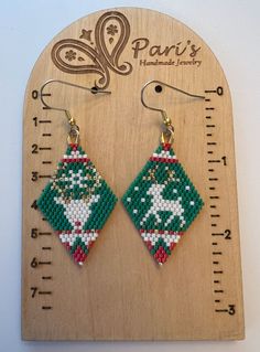 a pair of green and white beaded earrings sitting on top of a wooden ruler