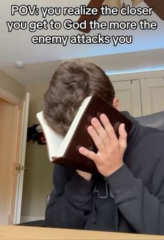 a man is hiding his face behind a book with the caption pov you relieze the closer you get to god the more than enemy attacks you