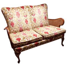 an old fashioned couch with floral fabric on it's back and armrests