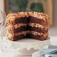 a chocolate cake is cut into pieces on a white plate with silverware and wine glasses