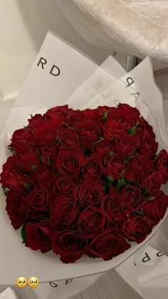 a bouquet of red roses sitting on top of a pile of white paper with emoticions