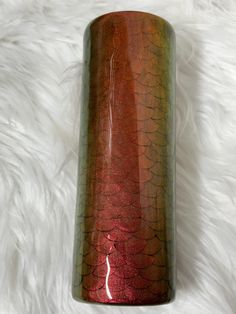 a red and green vase sitting on top of a white fur covered floor next to a wall