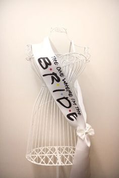 a white dress on display with a ribbon tied around the neck and an advertise