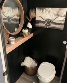 a bathroom with black walls and white fixtures, including a toilet in the corner next to a wooden shelf