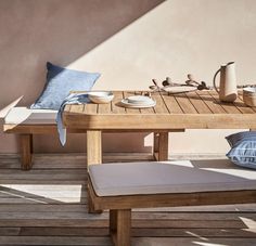 a wooden table sitting on top of a wooden floor next to a blue pillow and cup