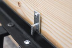 a close up of a metal handle on a wooden board with rivets and screws