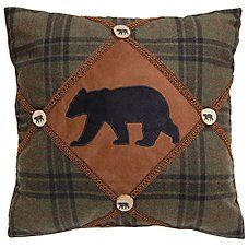 a brown and black bear pillow sitting on top of a green checkered pillow cover