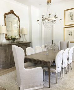 a dining room table with white chairs and a chandelier