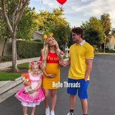 a man, woman and child are standing in the middle of a street with balloons