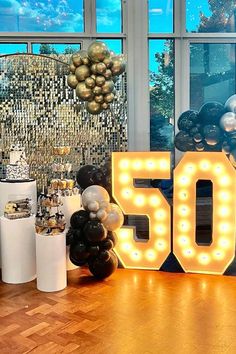 a 50th birthday party with balloons and lights on the floor, in front of a large sign that reads 50