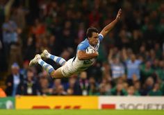 a rugby player is diving to catch the ball in front of an audience at a sporting event