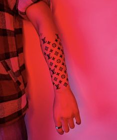 a person's arm with a tattoo on it in front of a pink background