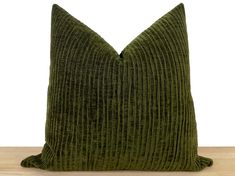 a green velvet pillow sitting on top of a wooden table