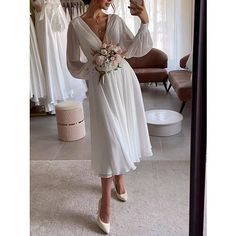 a woman taking a selfie in front of a mirror while wearing a white dress