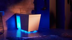 a blue light shines on the side of a white cabinet in a dimly lit room