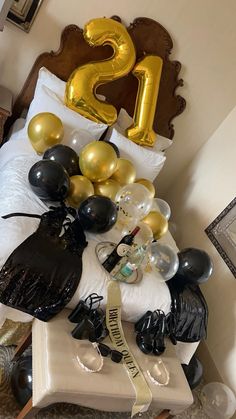 a bed with black and gold balloons in the shape of numbers on top of it