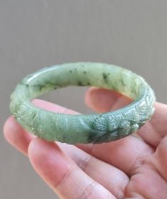 This Jadeite bangle outer is rounded and and flatten on the inside by hand. This jade bangle untreated Type-A jadeite jade. It has been polished on the inside and outside. The photos have not been altered or changed at all. *Bangle Shape: Flat Inner, Hand Carved Floral Design Round Outer *Color: Icy Cloudy Imperial Green, Apple Green (Moss-In-Snow) *Luster: Vitreous *Transparency: Translucent *Inside Width: 58.3mm *Bangle Width: 14.8 mm *Weight: 60 Grams *Size: Medium *Texture: Fine and Smooth * Green Carved Round Bangle, Carved Round Bangle For Formal Events, Carved Round Bangle For Formal Occasions, Carved Round Bracelets For Wedding, Carved Round Wedding Bracelets, Carved Formal Bangle, Wedding Carved Round Bracelets, Jade Bangle, Bluish Green