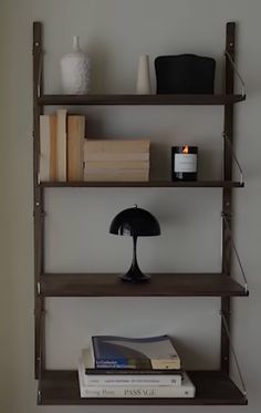 a shelf with books, lamp and other items on it in the corner of a room