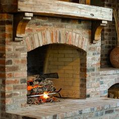 a brick fireplace with fire burning in it