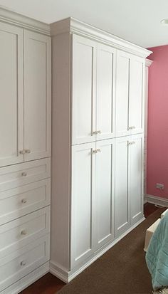 a bedroom with pink walls and white cabinets