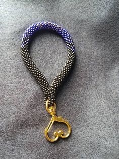 a blue and gold beaded lanyard with a golden metal hook on it's end