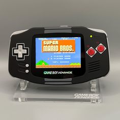 an image of a game boy advance with super mario bros on the screen and it's display stand