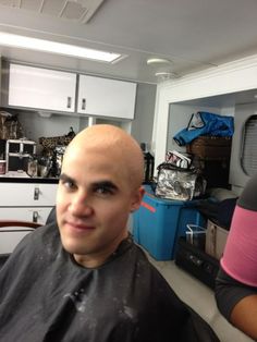 a man with a bald head sitting in a barbershop looking at the camera