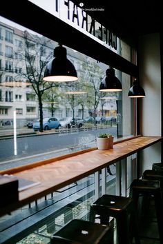 an empty restaurant with wooden tables and black lights hanging from the ceiling, overlooking a city street