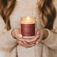 a woman holding a candle in her hands with the words christmas cookies written on it