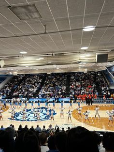 a group of people standing on top of a basketball court in front of a crowd