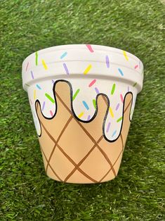 a paper cup with sprinkles and ice cream on it sitting in the grass