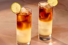 two tall glasses filled with ice and limes