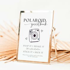 a polaroid guest book sitting on top of a table next to palm fronds