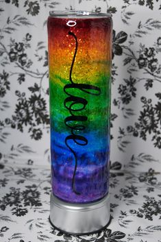 a rainbow colored tumble with the word love painted on it's side in black lettering