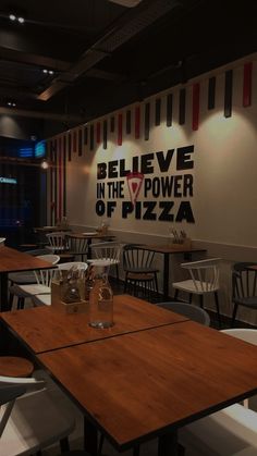 an empty restaurant with tables and chairs in front of a sign that says believe in the power of pizza