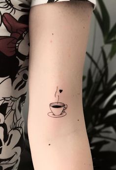 a woman's arm with a coffee cup tattoo on it