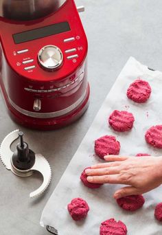 a person is making red cookies on a paper towel next to an electric blender