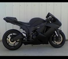 a black motorcycle parked in front of a white wall