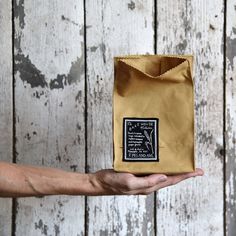 a person holding out a brown paper bag