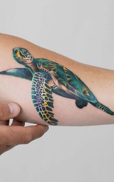 a woman's arm with a tattoo of a turtle on the inside of it