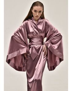 Evoking the polished sophistication of the geisha, the KAfemme long satin kimono is the epitome of elegance. Made of silk and satin blend in delicate lilac color the obi belt brings soft femininity to the silhouette. ✓ garment length - 147 cm/58'' ✓ wrap over style ✓ two sets of inside ties ✓ wide obi-tie is included Material Composition:  polyamide 60%, viscose 20%, polyester 10%, silk 7%, elastane 3% *CAN BE ORDERED IN 100% MULBERRY SILK* Model is 172 cm/67.6'' tall and wears size XS/S. Fancy Robe, Bridesmaid Robes Blue, Fancy Robes, Satin Dressing Gown, Silk Robes, Luxury Robes, Sheer Robe, Blue Kimono, Silk Kimono Robe