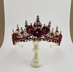 Introducing Kate our custom Dark Red Quinceanera Tiara - perfect for your special event! Whether it's your big day as a bride, a Quinceanera, or a pageant, this maroon tiara will be the crowning glory of your outfit. Crafted with exquisite attention to detail and dar red stones, flowers, maroon crystals, burgandy beads and it's sure to add a hint of royalty to your look. Our unique custom design features an intricately detailed setting with finely cut stones that sparkle and glisten in the light Red Quince Crown Gold, Burgundy Quince Theme, Dark Red Quinceanera Theme, Burgundy And Gold Quinceanera Theme, Red And Gold Tiara, Burgundy Quinceanera Theme, Red Quinceanera Theme, Burgundy Quince, Masquerade Quince