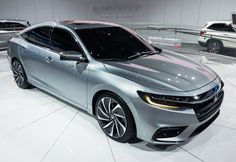 a silver car is on display in a showroom with other cars behind it,