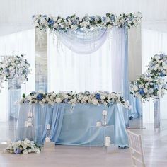 a blue and white wedding set up with flowers