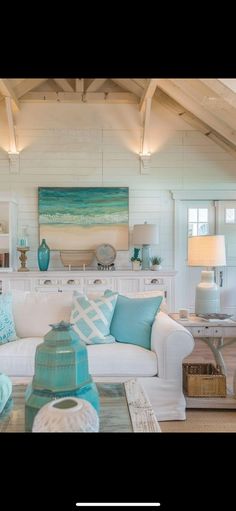 a living room filled with white furniture and blue pillows on top of it's couches