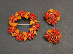 "Here you have an absolutely beautiful wreath brooch and clip on earring set that's decorated with blood orange rhinestones.  This set is fantastic - the pictures don't do it justice! The wreath is decorated in sparkling blood orange flowers with matte orange leaves. The accompany earrings look like clusters of sparkling flowers with the matte orange leaves sprinkled around the edges.  This set a signed \"Weiss NY\" and is circa the 1950s. The brooch has its clasp still intact and the earrings a Cake Makeover, Sparkling Flowers, Fancy Event, Clip On Earring, Orange Leaves, Orange Leaf, Orange Cake, Rhinestone Flower, Vintage Glam